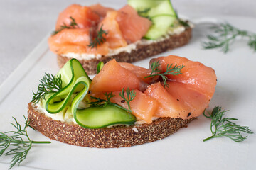 Sandwiches with salted salmon and cucumber on white board