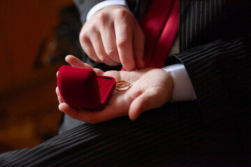 Man Opening Red Ring Box With Wedding Rings