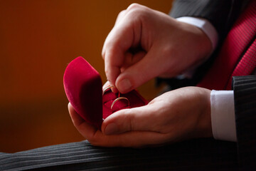 Hands holding red box with gold rings