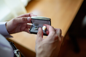 Groom preparing for wedding ceremony, holding cufflinks