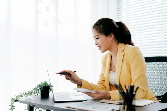 Young Asian woman doing financial accounting and taxes for a company Organizing account analysis reports Investment information Financial and tax system concepts - Powered by Adobe