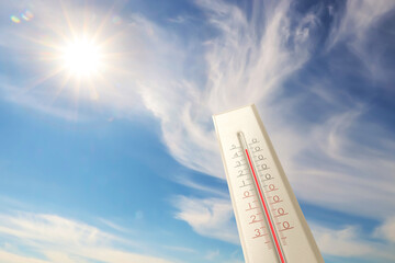 Extremely high temperature on thermometer against blue sky on sunny day. Summer weather