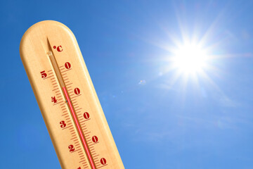 Extremely high temperature on thermometer against blue sky on sunny day. Summer weather