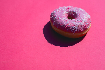 Bright Pink Donut With Colorful Sprinkles on Vibrant Red Background Exuding Sweetness and Fun