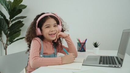 Side view of smart girl take off headphone and doing homework in self study. Caucasian schoolgirl...