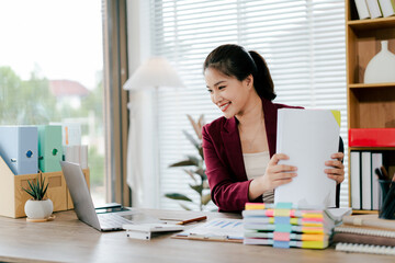 Female employee working with pile of documents to search for information and check documents on desk in office. Accounting income, expenses, tax records and hard work.