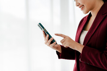 Portrait of young woman holding smartphone, typing text, chatting with friends on social network. Concept of using mobile application, online shopping, opening website, ordering food, business.