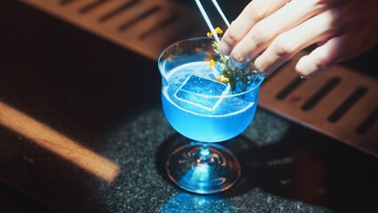 Closeup hand bartender using strainer mixed vodka in blue hawaii cocktail at luxurious counter....