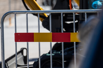 construction barrier with red and yellow reflective warning stripe on metal fence closeup...