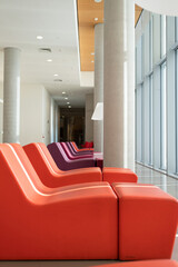 The interior of a modern apartment or hotel lobby with comfortable red couches, creating a clean,...