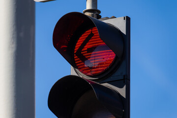 red left arrow traffic light signal on urban street against clear blue sky close up of illuminated...