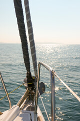 Adventure on a sailboat, sailing into the horizon on a summers day showing the bow of a yacht with sails and sunshine