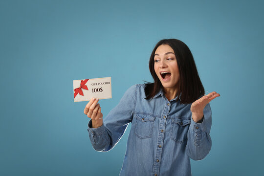Young excited woman wear pajamas jam sleep eye mask rest relaxing at home point index finger on gift voucher flyer mock up isolated on pastel blue background studio. Good mood night bedtime concept