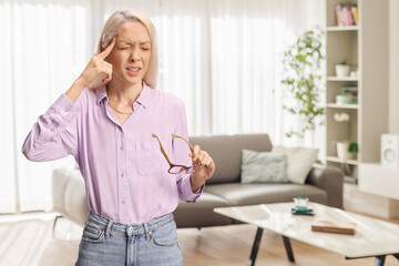 Young woman with headache holding glasses