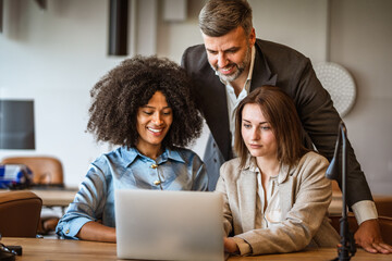 Helpful male boss mentor explain new project to young females workers