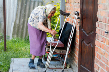 An old woman navigating outside with the aid of crutches or a walker, her determined hands showing...