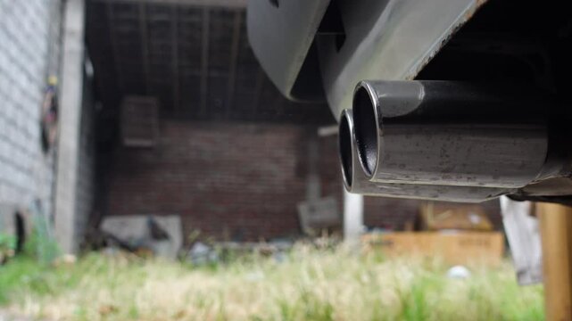 Close-up detail of a car muffler during engine startup, capturing subtle vibrations and initial exhaust emissions