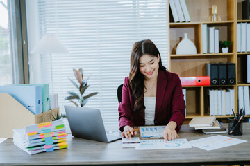 Smiling Asian Businesswoman Working: A young, smiling Asian businesswoman works diligently at her...