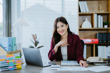 Smiling Asian Businesswoman Working: A young, smiling Asian businesswoman works diligently at her...