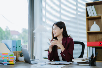 Smiling Asian Businesswoman Working: A young, smiling Asian businesswoman works diligently at her...