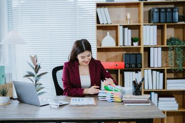 Smiling businesswoman works online using laptop in office. Young pro woman types on keyboard. Successful manager works at desk. Happy entrepreneur uses computer. Modern corporate workplace. Online