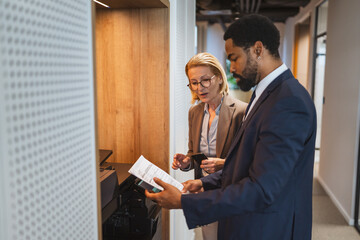 Two multicultural businesspeople talk while scan document on a scanner