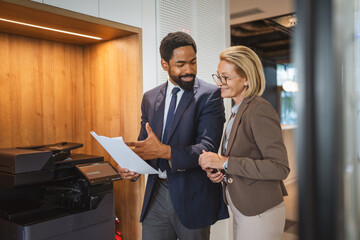 female and male colleague stand by the copy machine and discuss