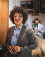 Portrait of black businesswoman stand and smile in hallway of company