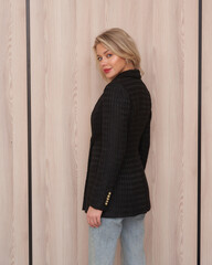 Blonde woman with red lipstick and wavy hair in black textured blazer with golden buttons and blue...