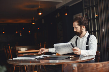 Bearded man sits at a table and drinks alcohol.