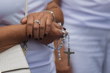 Details of hands of religious person holding crucifix.