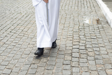 Half-length photo of an unidentified religious follower walking down the street wearing traditional...