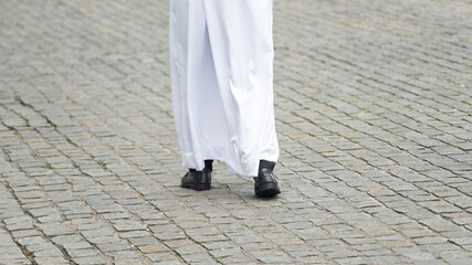 Half-length photo of an unidentified religious follower walking down the street wearing traditional clothing.