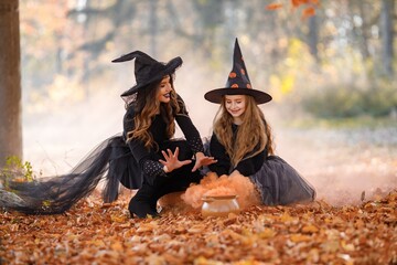Portrait of mother and daughter in witch costumes in autumn forest
