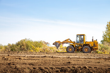 Yellow bulldozer at a construction site. Big wheel excavator leveling and clearing the land plot...
