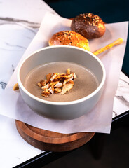 Creamy Mushroom Soup with Croutons and Bread Rolls on Wooden Board and Marble Table