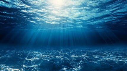 Underwater view of deep blue ocean with sun rays penetrating through the surface and marine particles floating in clear water