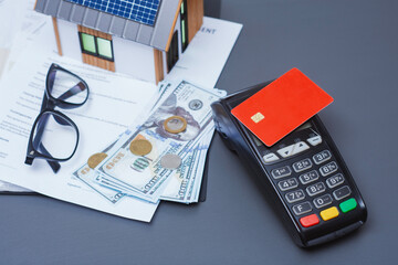 Payment terminal for credit card payment, US dollars and solar powered house model. Concept of property payment and real estate transactions for green housing.