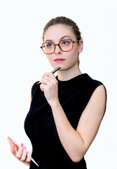 Une femme avec des lunettes tenant un stylo et un bloc-notes, ayant l'air pensive