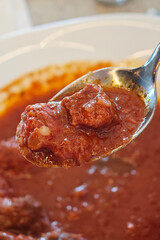 A spoonful of meat sauce is being scooped out of a bowl