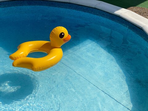 Inflatable duck-shaped ring in children's swimming pool on sunny summer day. Water safety. Copy space. 