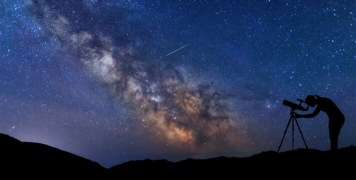Silhouette stargazer woman looking through telescope at the stars and Milky way. Scenery Landscape with night starry sky and silhouette of standing woman with telescope.