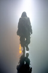 Back view of a faceless model walking into fog in techwear duster coat, wide tactical pants, 