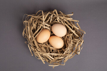 Three brown eggs in a nest made of shredded paper – top view