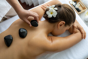 Hot stone massage at spa salon in luxury resort with day light serenity ambient, blissful woman...