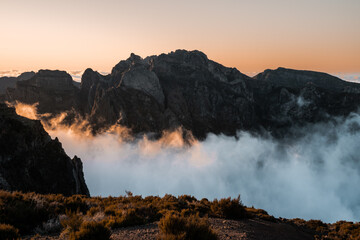 Sunset view of Pico do Arieiro mountain with dramatic contrast and clouds cutting across lower...