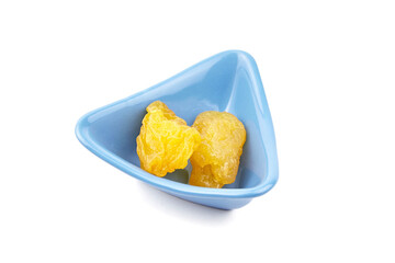 Dehydrated yellow pears in a blue triangular bowl, showcasing their unique texture and color,...