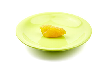Dehydrated yellow pear placed on a vibrant green plate, showcasing a glossy texture and inviting...