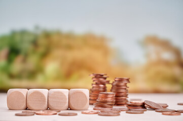 Single wooden block and several coins symbolizing financial stability, savings, and simplicity in...