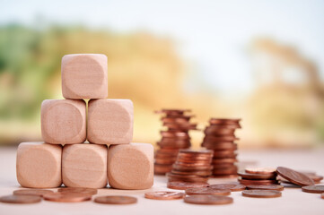 Wooden blocks stacked in pyramid formation beside coins symbolizing financial planning, growth, and...